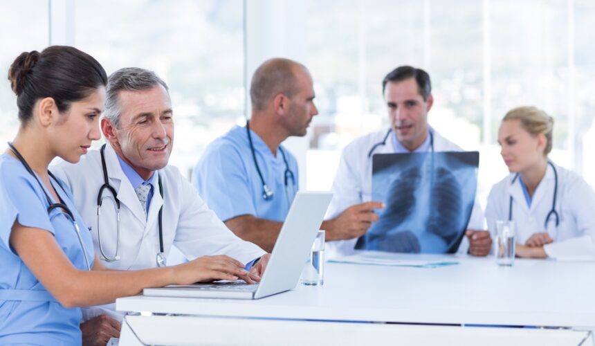 Doctors-using-computer-whiles-theirs-colleagues-looking-at-Xray-in-medical-office The Role of CINs in Securing Value-Based Contracts